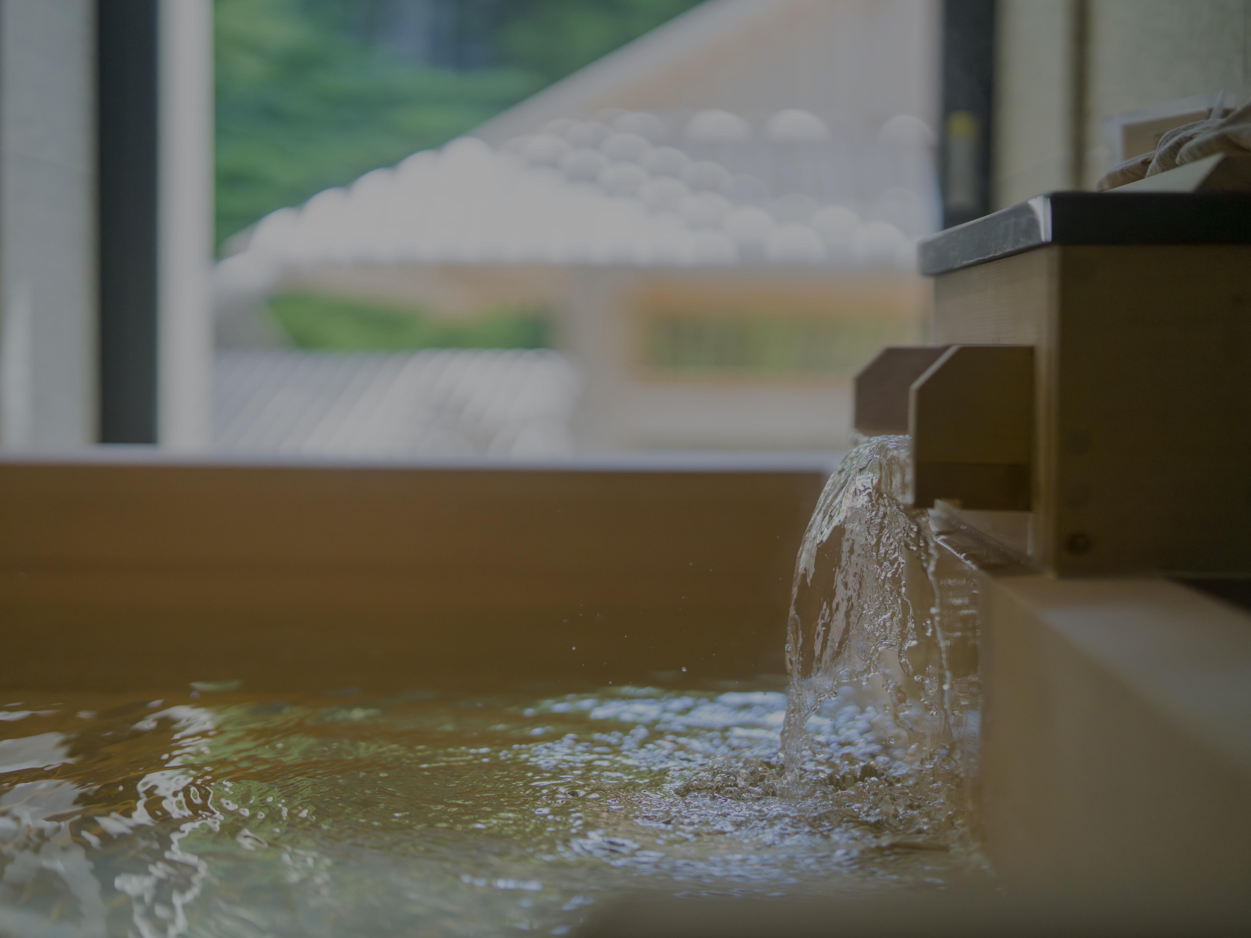 Water flows into wooden bath, creating serene atmosphere at Banyan Tree Higashiyama Kyoto.